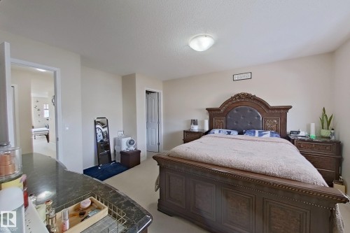This room features neutral-toned walls, a textured ceiling, and carpeted flooring - 3120 25 Avenue Nw, Edmonton, AB - Indoor Photo Showing Bedroom