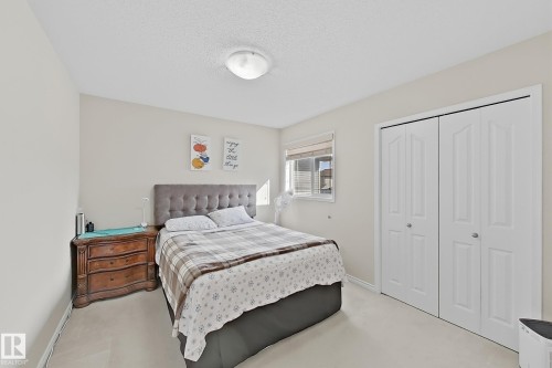 This room features light-colored walls and carpeting, a window with blinds, and white bi-fold closet doors - 3120 25 Avenue Nw, Edmonton, AB - Indoor Photo Showing Bedroom