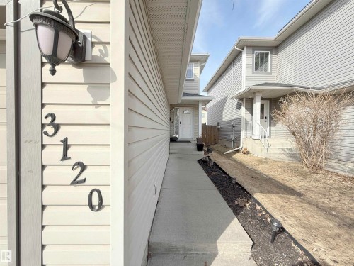 The property features a concrete walkway leading to the entrance, with exterior siding and a porch light fixture - 3120 25 Avenue Nw, Edmonton, AB - Outdoor