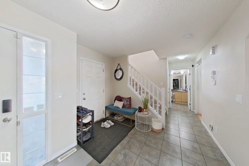The property features a bright entryway with tiled flooring, a white staircase, and a doorway leading to another area of the home - 3120 25 Avenue Nw, Edmonton, AB - Indoor Photo Showing Other Room