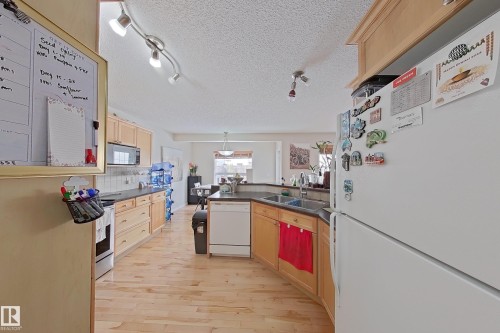 The kitchen features light wood cabinetry, a white refrigerator, and track lighting - 3120 25 Avenue Nw, Edmonton, AB - Indoor Photo Showing Kitchen With Double Sink