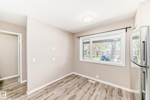 Bright room featuring a large window with white trim, wood-finish flooring, and a modern ceiling light fixture - 2578 138A Avenue, Edmonton, AB - Indoor Photo Showing Other Room