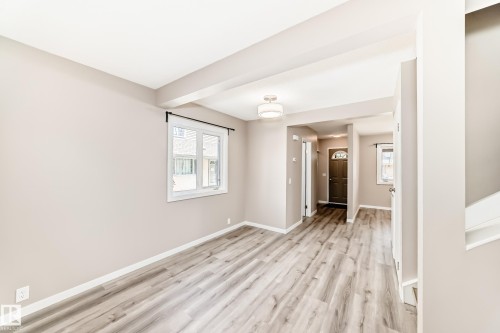 Spacious room featuring wood-finish flooring, neutral wall tones, a modern ceiling light fixture, and white trim - 2578 138A Avenue, Edmonton, AB - Indoor Photo Showing Other Room