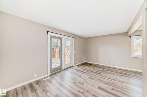 Spacious room featuring wood-finish flooring, neutral wall tones, white baseboards, and a white ceiling - 2578 138A Avenue, Edmonton, AB - Indoor Photo Showing Other Room