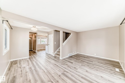 Open concept living space featuring wood-finish flooring, neutral wall tones, white trim, and ample natural light from multiple windows - 2578 138A Avenue, Edmonton, AB - Indoor Photo Showing Other Room