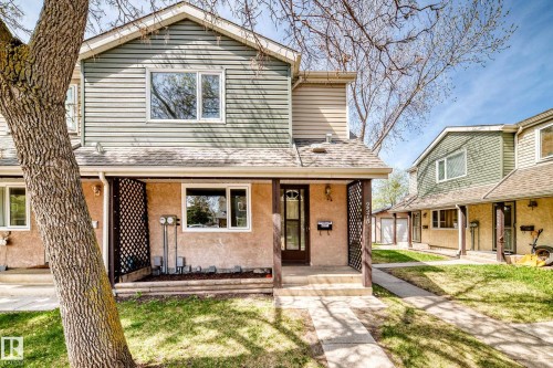 Two-story residence featuring a covered front porch with lattice detailing, stucco and siding exterior, and a central entryway with a dark-framed door - 2578 138A Avenue, Edmonton, AB - Outdoor With Deck Patio Veranda