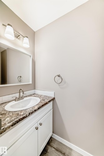 Bathroom vanity featuring white cabinetry, a speckled countertop, an undermount sink, and a brushed nickel faucet - 2578 138A Avenue, Edmonton, AB - Indoor Photo Showing Bathroom