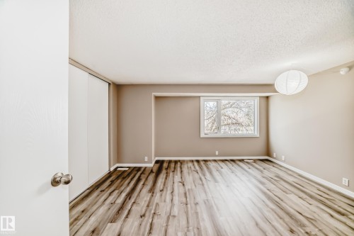 Spacious room featuring wood-finish flooring, neutral-toned walls, and a large window - 2578 138A Avenue, Edmonton, AB - Indoor Photo Showing Other Room