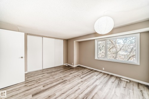 Bedroom featuring wood-finish flooring, a large window, a ceiling-mounted light fixture, and sliding closet doors - 2578 138A Avenue, Edmonton, AB - Indoor Photo Showing Other Room
