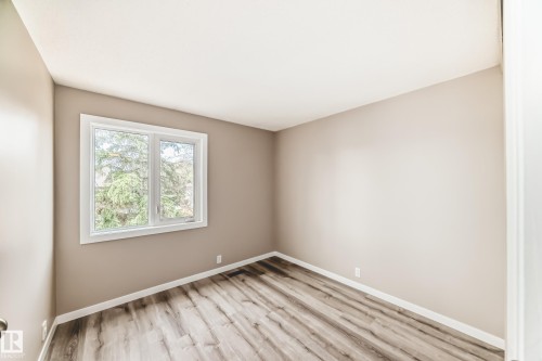 Interior room featuring a large window, neutral wall paint, wood-finish flooring, and white baseboards - 2578 138A Avenue, Edmonton, AB - Indoor Photo Showing Other Room
