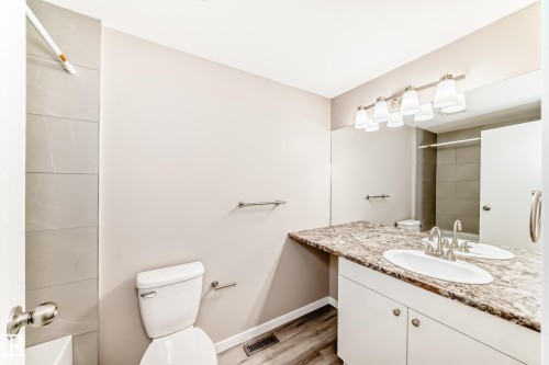 Bathroom featuring a vanity with a stone-look countertop, undermount sink, and brushed nickel fixtures - 2578 138A Avenue, Edmonton, AB - Indoor Photo Showing Bathroom
