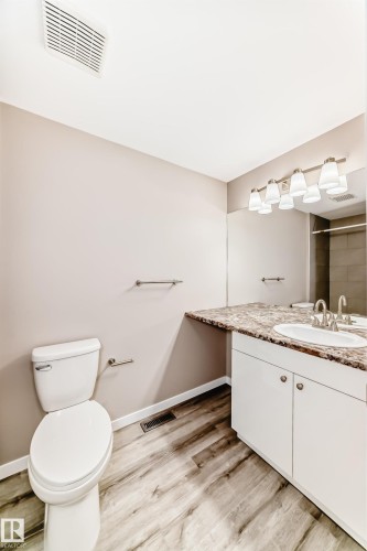Bathroom featuring a white vanity with a single basin, a mottled countertop, and wood-finish flooring - 2578 138A Avenue, Edmonton, AB - Indoor Photo Showing Bathroom