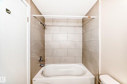 Bathtub with subway tile surround, chrome fixtures, and a white shower rod - 2578 138A Avenue, Edmonton, AB - Indoor Photo Showing Bathroom