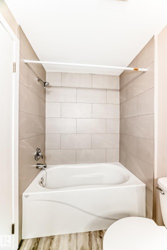 White bathtub and shower combination with light-toned rectangular wall tile surround - 2578 138A Avenue, Edmonton, AB - Indoor Photo Showing Bathroom