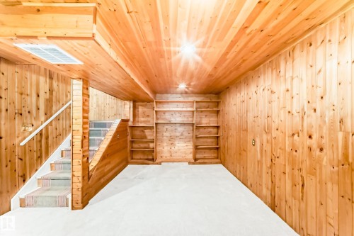 Carpeted room featuring wood-paneled walls and ceiling, built-in shelving, and a carpeted staircase with a white handrail - 2578 138A Avenue, Edmonton, AB - Indoor Photo Showing Other Room
