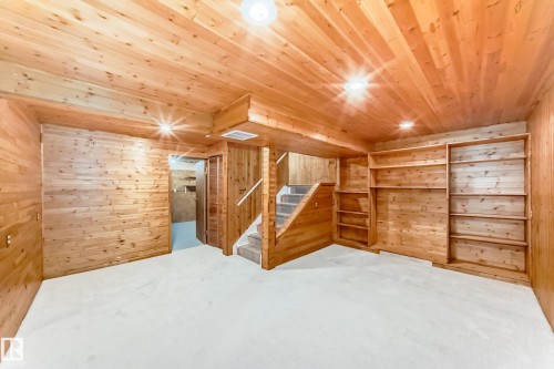 Wood-paneled room featuring extensive built-in shelving, a carpeted staircase, and recessed lighting - 2578 138A Avenue, Edmonton, AB - Indoor Photo Showing Other Room