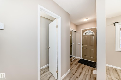 Entryway featuring wood-finish flooring, a paneled front door with an arched transom, and a mirrored sliding closet door - 2578 138A Avenue, Edmonton, AB - Indoor Photo Showing Other Room