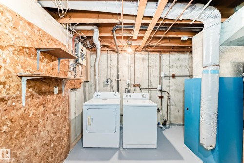 Dedicated laundry area featuring a washer and dryer, concrete foundation walls, painted flooring, and exposed ceiling joists - 2578 138A Avenue, Edmonton, AB - Indoor Photo Showing Laundry Room