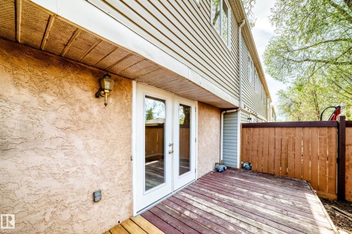 Private wooden deck with double glass-paneled patio doors, textured stucco exterior, and a privacy fence - 2578 138A Avenue, Edmonton, AB - Outdoor With Exterior