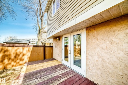 Outdoor wood deck with a privacy fence, textured stucco exterior, and white frame double doors - 2578 138A Avenue, Edmonton, AB - Outdoor