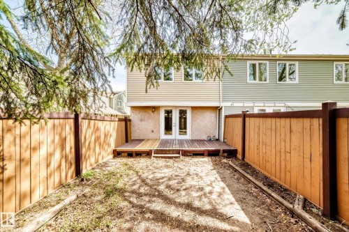Rear exterior featuring a ground-level wood deck, double glass patio doors, and a combination of horizontal siding and stucco finishes - 2578 138A Avenue, Edmonton, AB - Outdoor With Deck Patio Veranda