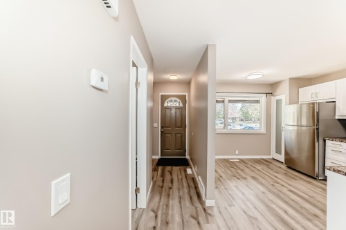 Entryway featuring wood-finish flooring, a contemporary front door with an arched glass insert, and a modern thermostat - 2578 138A Avenue, Edmonton, AB - Indoor