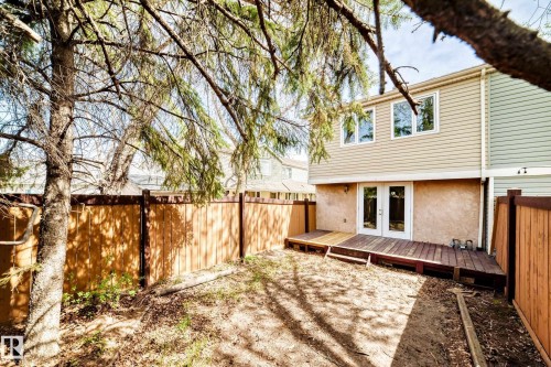 Rear exterior featuring a multi-level wood deck, white French doors, and two upper-level windows - 2578 138A Avenue, Edmonton, AB - Outdoor