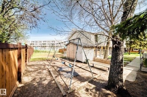 Private backyard featuring a wooden privacy fence, mature trees, a swing set, and a wooden bench - 2578 138A Avenue, Edmonton, AB - Outdoor