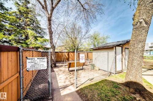 Fenced outdoor area featuring a storage shed with dual doors, a wooden bench, a swing set, and a chain-link gate - 2578 138A Avenue, Edmonton, AB - Outdoor