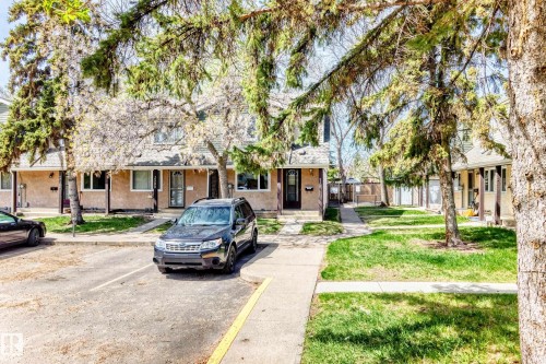 Townhouse facade featuring beige stucco exterior, white trim windows, and dark entry doors - 2578 138A Avenue, Edmonton, AB - Outdoor