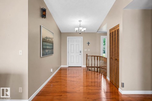 Entryway featuring wood-finish flooring, a white paneled entry door, and a traditional chandelier - 250 197 Avenue, Edmonton, AB - Indoor Photo Showing Other Room