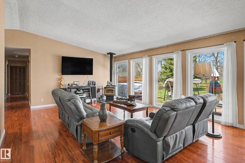 Living area with wood-finish flooring, a wall-mounted television, and a wood-burning stove - 250 197 Avenue, Edmonton, AB - Indoor Photo Showing Living Room