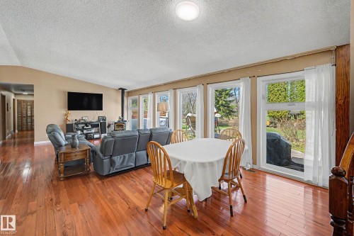 Open-concept living area with rich wood-finish flooring, a vaulted ceiling, and multiple large windows providing abundant natural light - 250 197 Avenue, Edmonton, AB - Indoor
