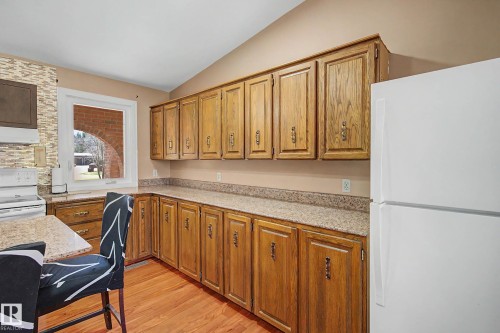 Kitchen featuring extensive wood cabinetry, speckled countertops, and wood-finish flooring - 250 197 Avenue, Edmonton, AB - Indoor
