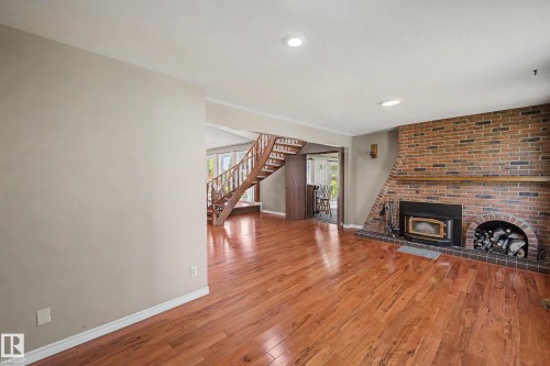 Brick fireplace with wood-burning insert, integrated wood storage, and a substantial wood mantel - 250 197 Avenue, Edmonton, AB - Indoor Photo Showing Living Room With Fireplace