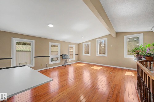 Open-concept room featuring wood-finish flooring, numerous windows, recessed lighting, and a vaulted ceiling with an exposed beam - 250 197 Avenue, Edmonton, AB - Indoor