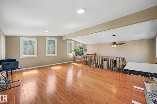 Expansive interior space featuring wood-finish flooring, numerous windows, recessed lighting, a ceiling fan, and a wood railing system - 250 197 Avenue, Edmonton, AB - Indoor Photo Showing Other Room