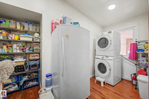 Dedicated utility area featuring wood-finish flooring, a stacked washer and dryer, and a built-in window - 250 197 Avenue, Edmonton, AB - Indoor Photo Showing Laundry Room