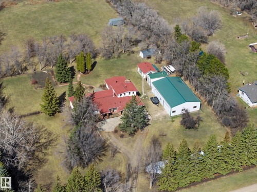 Expansive property featuring a primary residence with a red roof, a substantial green-roofed outbuilding, mature trees, open green spaces, and a gravel driveway - 250 197 Avenue, Edmonton, AB - Outdoor With View