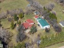 Expansive property featuring a primary residence with a red roof, a substantial green-roofed outbuilding, mature trees, open green spaces, and a gravel driveway - 250 197 Avenue, Edmonton, AB  - Outdoor With View 
