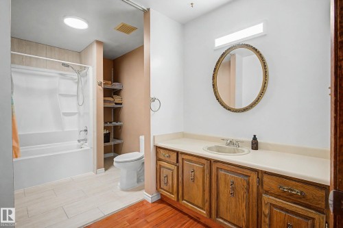 Bathroom featuring a shower-tub combination, a vanity with a light-toned countertop, and wood-finish cabinetry - 250 197 Avenue, Edmonton, AB - Indoor Photo Showing Bathroom