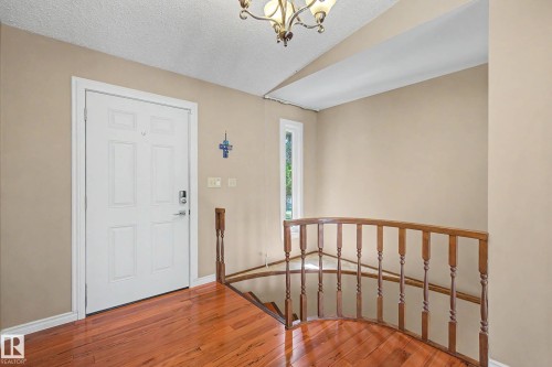 Foyer featuring wood-finish flooring, a white panel door, and a wooden staircase railing - 250 197 Avenue, Edmonton, AB - Indoor Photo Showing Other Room