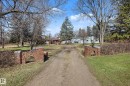 Brick entry pillars with house numbers 250, gravel driveway, and surrounding mature trees - 250 197 Avenue, Edmonton, AB  - Outdoor 