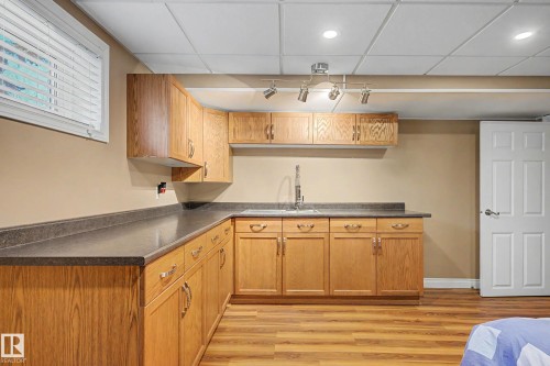 Kitchenette featuring wood-finish cabinetry, dark countertops, and a stainless steel sink with a gooseneck faucet - 250 197 Avenue, Edmonton, AB - Indoor