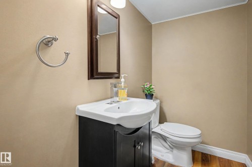 Bathroom featuring a dark wood-finish vanity with an integrated white sink, a coordinating dark wood-finish framed mirror, and wood-finish flooring - 250 197 Avenue, Edmonton, AB - Indoor Photo Showing Bathroom