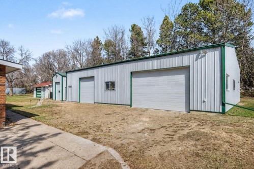Commerical Grade Shop, 60'x40', Spacious corrugated metal outbuilding featuring two large garage doors, multiple windows, and a green trim - 250 197 Avenue, Edmonton, AB - Outdoor With Exterior