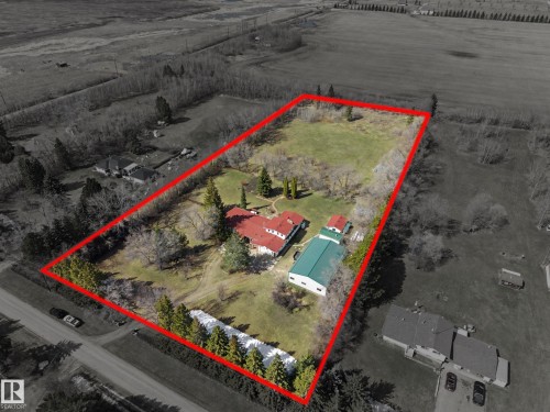 Expansive property featuring a red-roofed main residence, a large detached green-roofed building, and a substantial open land area - 250 197 Avenue, Edmonton, AB -  With View