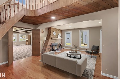 Living area featuring wood-finish flooring, a brick fireplace with a wood-burning stove, and recessed lighting - 250 197 Avenue, Edmonton, AB - Indoor With Fireplace