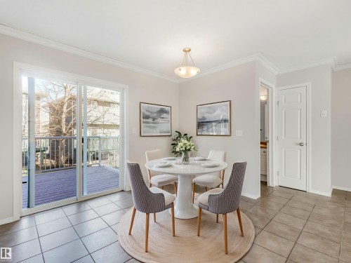 Dining area featuring tile flooring, crown molding, and a sliding glass door leading to an outdoor deck with white railings - 17 15128 22 Street, Edmonton, AB - Indoor Photo Showing Dining Room
