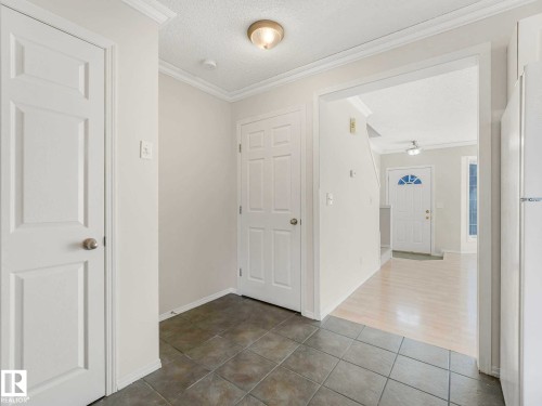 Entryway featuring neutral-toned tile flooring, white interior doors, and crown molding - 17 15128 22 Street, Edmonton, AB - Indoor Photo Showing Other Room